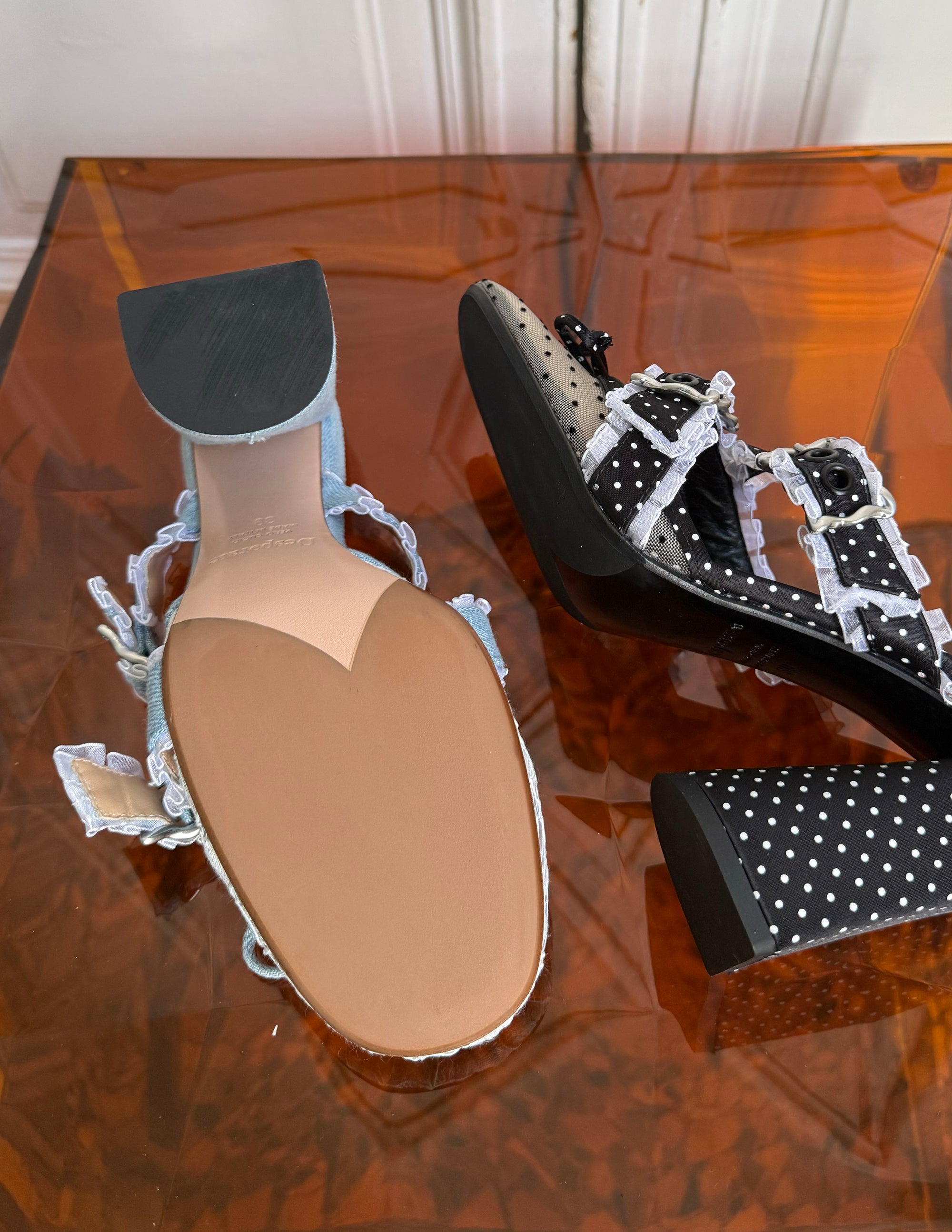 Pair of high-heeled shoes with polka dot design on a reflective surface