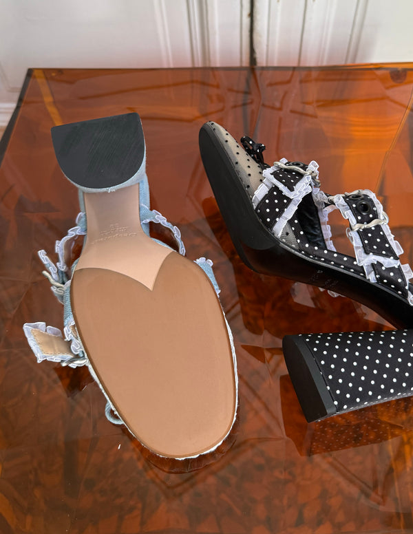 Pair of high-heeled shoes with polka dot design on a reflective surface