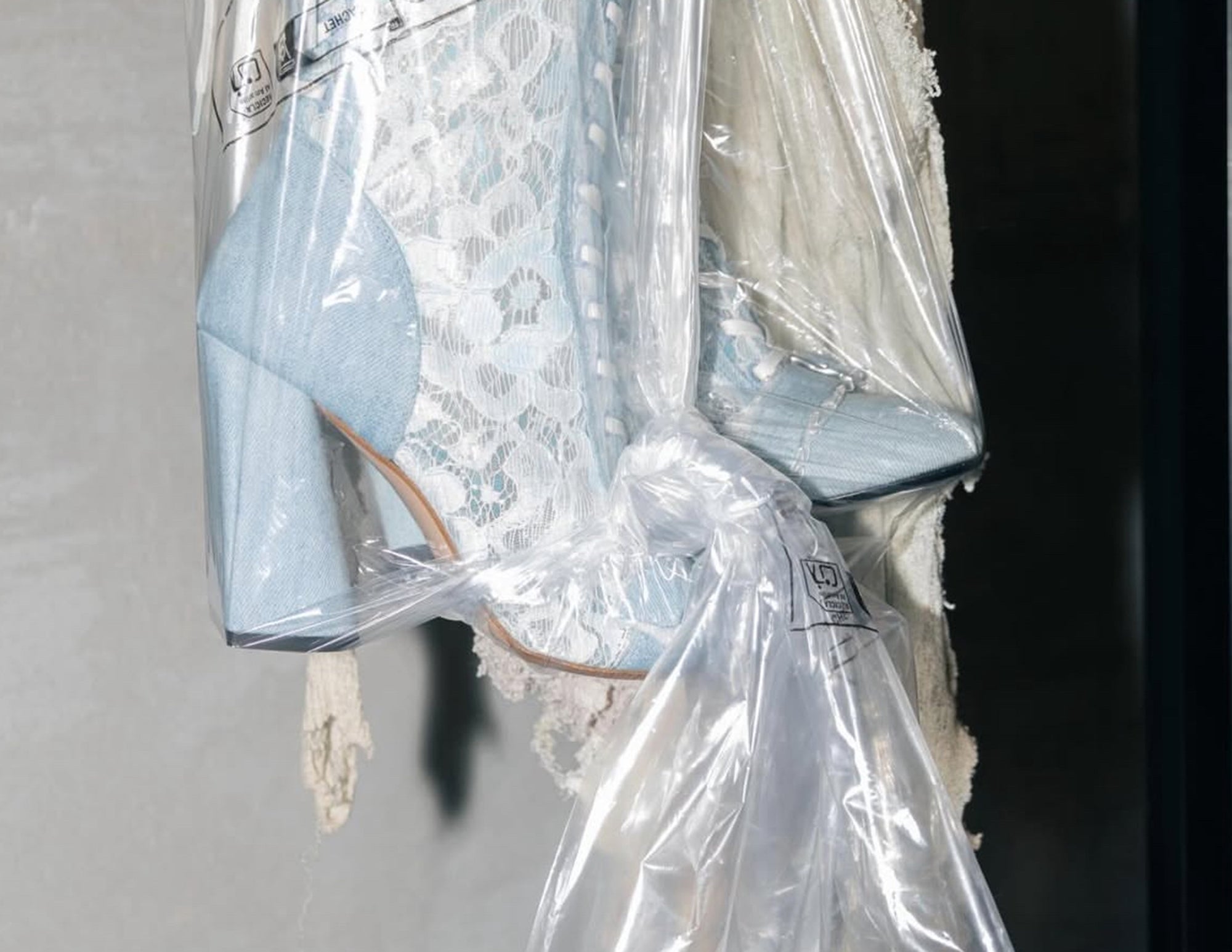 Light blue high-heeled shoes with a lace garment on a gray background